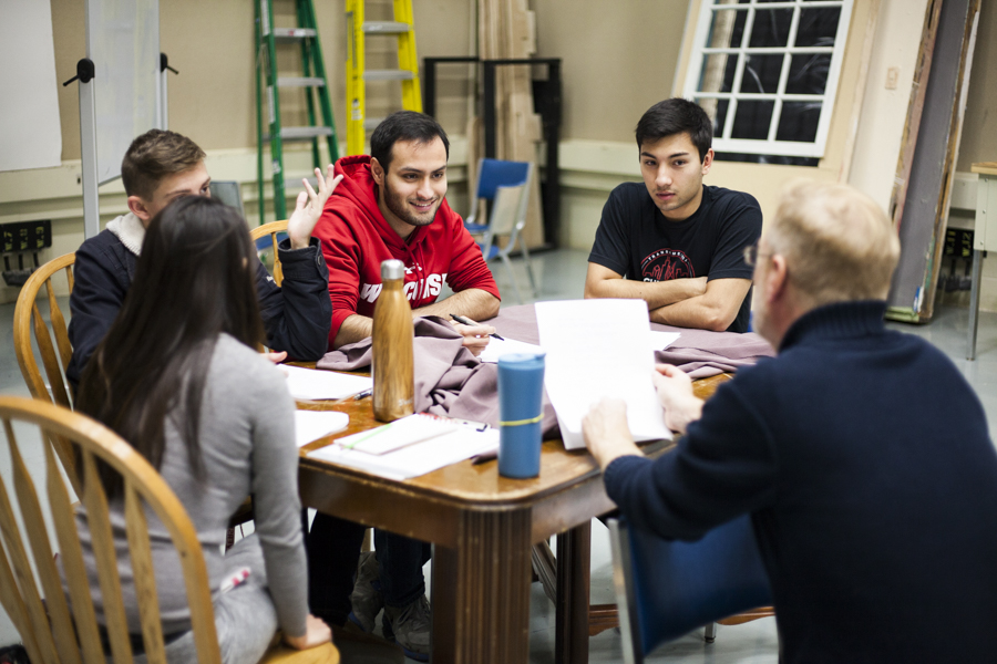 Student production group meeting in a studio to look over a script. 
